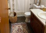 3. A neat bathroom with a toilet, sink, and a colorful rug adding warmth.